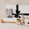 Load image into Gallery viewer, Lavender and Pine Sunday Sauce Gift Box front view featuring Bella Cucina bucatini pasta, Le Marké olive oil, French Farm L'Epicurien sweet garlic and herbs, Bella Cucina arrabbiata sauce, stainless garlic rocker, Natural OliveWood pasta spoon, and Kaf Home grey linen napkins in white magnetic gift box