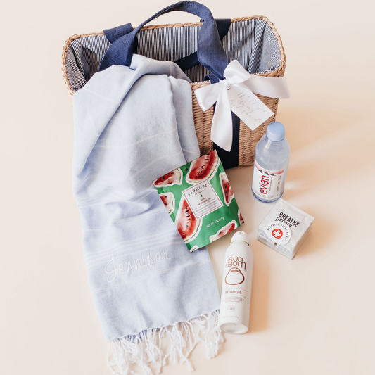 Beach bachelorette welcome gift basket by Lavender + Pine featuring a personalized towel, watermelon sheet mask, Sun Bum sunscreen, Evian water, and hangover essentials.
