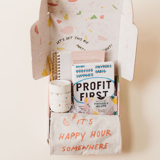 Curated client gift box featuring Profit First book, terrazzo tumbler, notebook, pineapple mojito gummies, and ‘It’s Happy Hour Somewhere’ tee – styled by Lavender + Pine.
