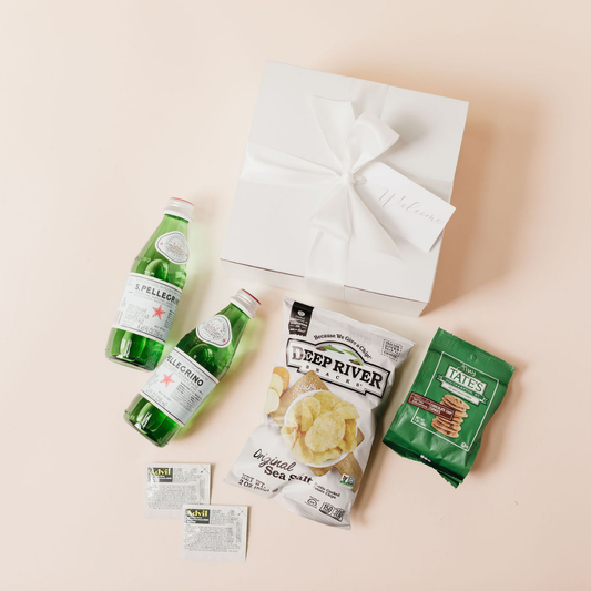 DIY wedding welcome gift box with San Pellegrino sparkling water, Deep River kettle chips, Tate’s Bake Shop cookies, Advil packets, and a white gift box tied with ribbon and a ‘Welcome’ tag - ideal for guest hospitality and 2025 wedding trends.