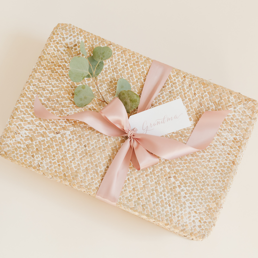 Mother’s Day gift box for Grandma with blush pink ribbon, eucalyptus sprig, and woven neutral wrapping – curated by Lavender + Pine