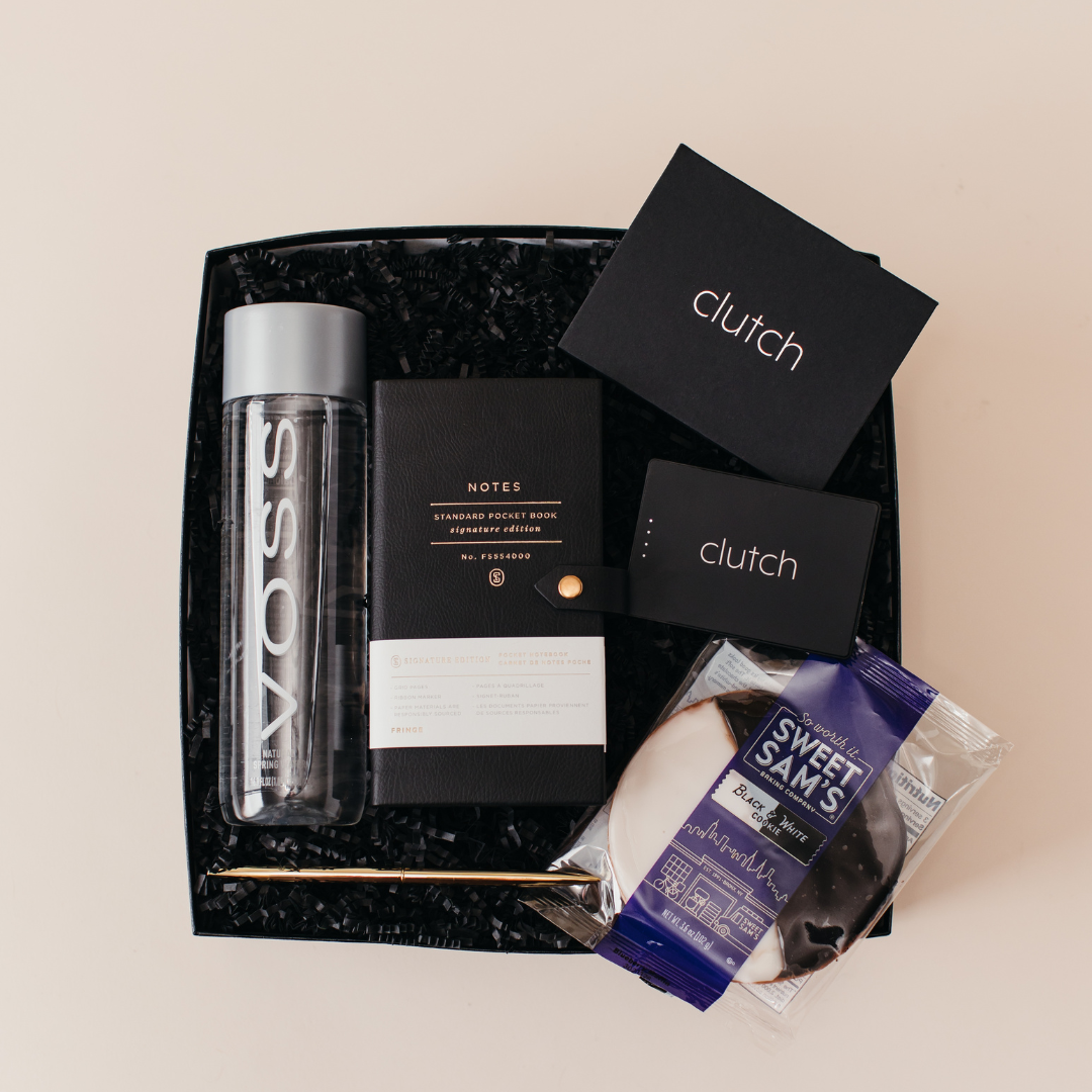 NYC Conference Collection welcome gift box with Voss water, notebook, gold pen, Clutch charger, and black and white cookie, Lavender + Pine