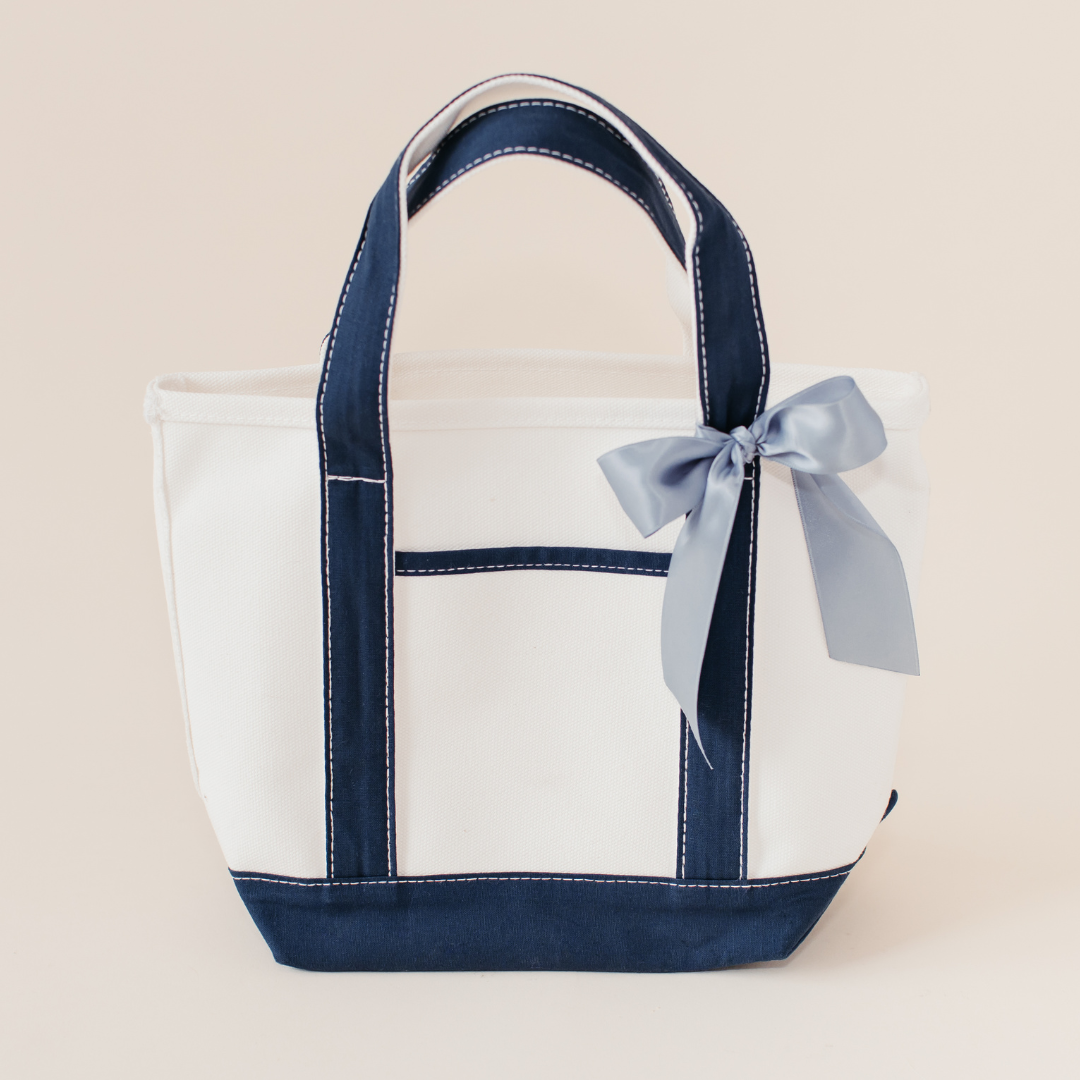 Navy and white canvas wedding welcome tote bag with light blue ribbon bow, used for summer wedding guest gifts by Lavender + Pine Gifting.