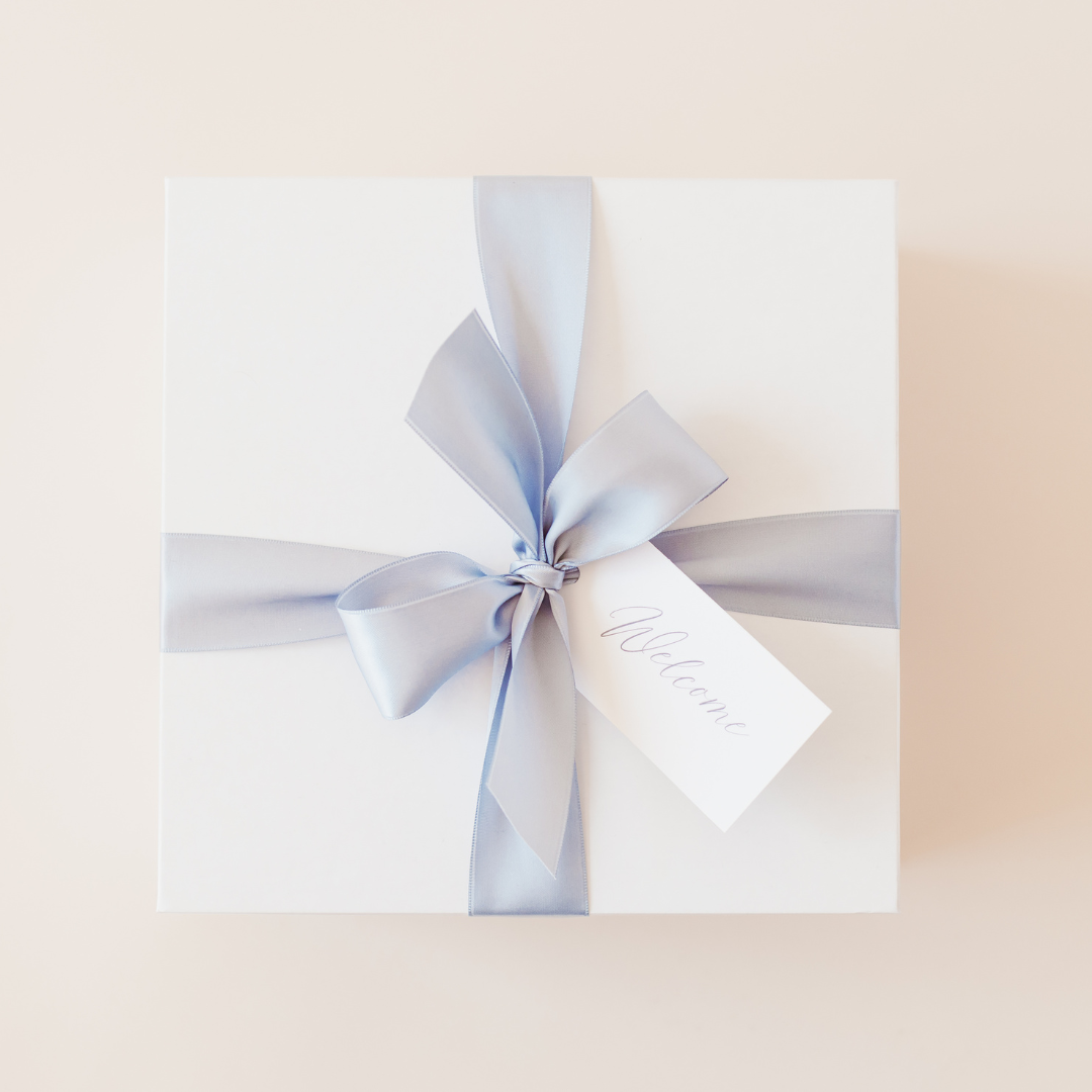 Wedding welcome gift box wrapped with light blue ribbon and Welcome tag, ready for hotel check-in or room drop distribution - Lavender + Pine Gifting