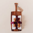 Load image into Gallery viewer, Housewarming gift set with an Ironwood acacia wood paddle cutting board, olive wood salt and pepper mills, and striped linen tea towels tied with burgundy satin ribbon
