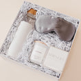 Load image into Gallery viewer, Lavender and Pine Rest and Restore Gift Box angle view featuring Soma glass water bottle, Pure Sol silk sleep mask, Roote lavender candle, and Shinery radiance towelettes in white luxe two piece gift box
