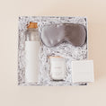 Load image into Gallery viewer, Lavender and Pine Rest and Restore Gift Box detail view featuring Soma glass water bottle, Pure Sol silk sleep mask, Roote lavender candle, and Shinery radiance towelettes in white luxe two piece gift box
