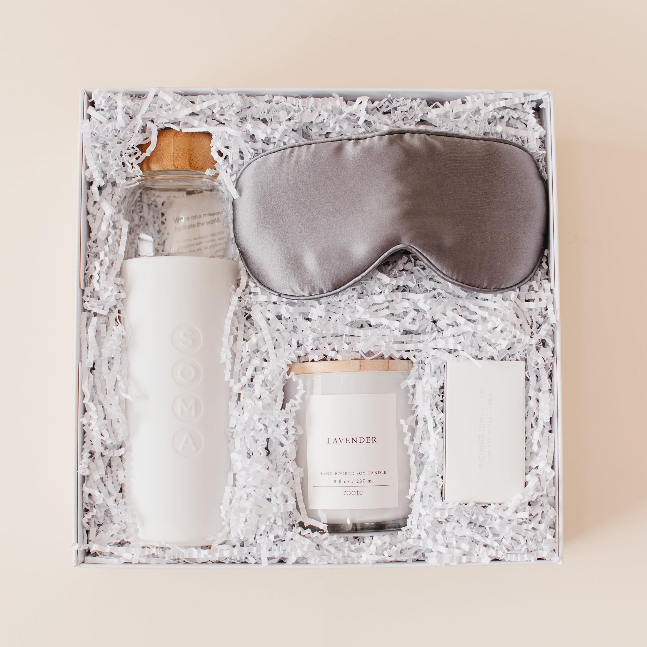 Lavender and Pine Rest and Restore Gift Box featuring Soma glass water bottle, Pure Sol silk sleep mask, Roote lavender candle, and Shinery radiance towelettes in white luxe two piece gift box