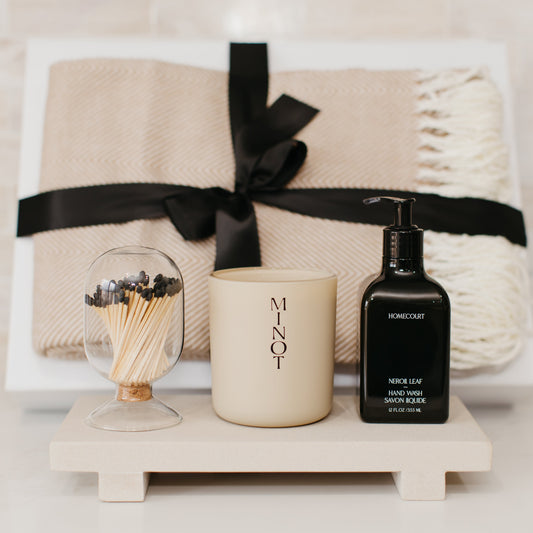 Lavender and Pine Sanctuary Gift Box close up view featuring Minot candle, Homecourt Neroli Leaf hand wash, black tip apothecary matches, Fennco Styles throw blanket, and Luxe B Co sandstone trivet riser in white magnetic gift box