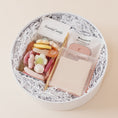 Load image into Gallery viewer, Lavender and Pine Desktop Edit gift box overhead angle featuring Scandy Candy Swedish candy, Touchland Rosewater Glow Mist, gold pen, and cream tabbed sticky notes in white round gift box
